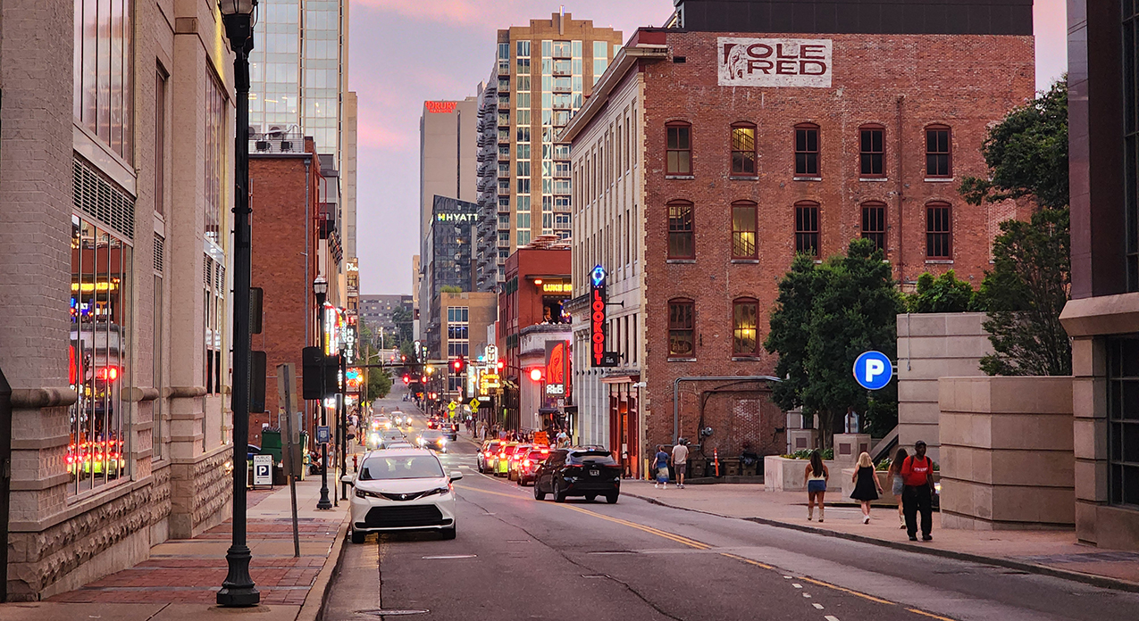 Nighttime scene of Broadway in Nashville with neon lights and crowds