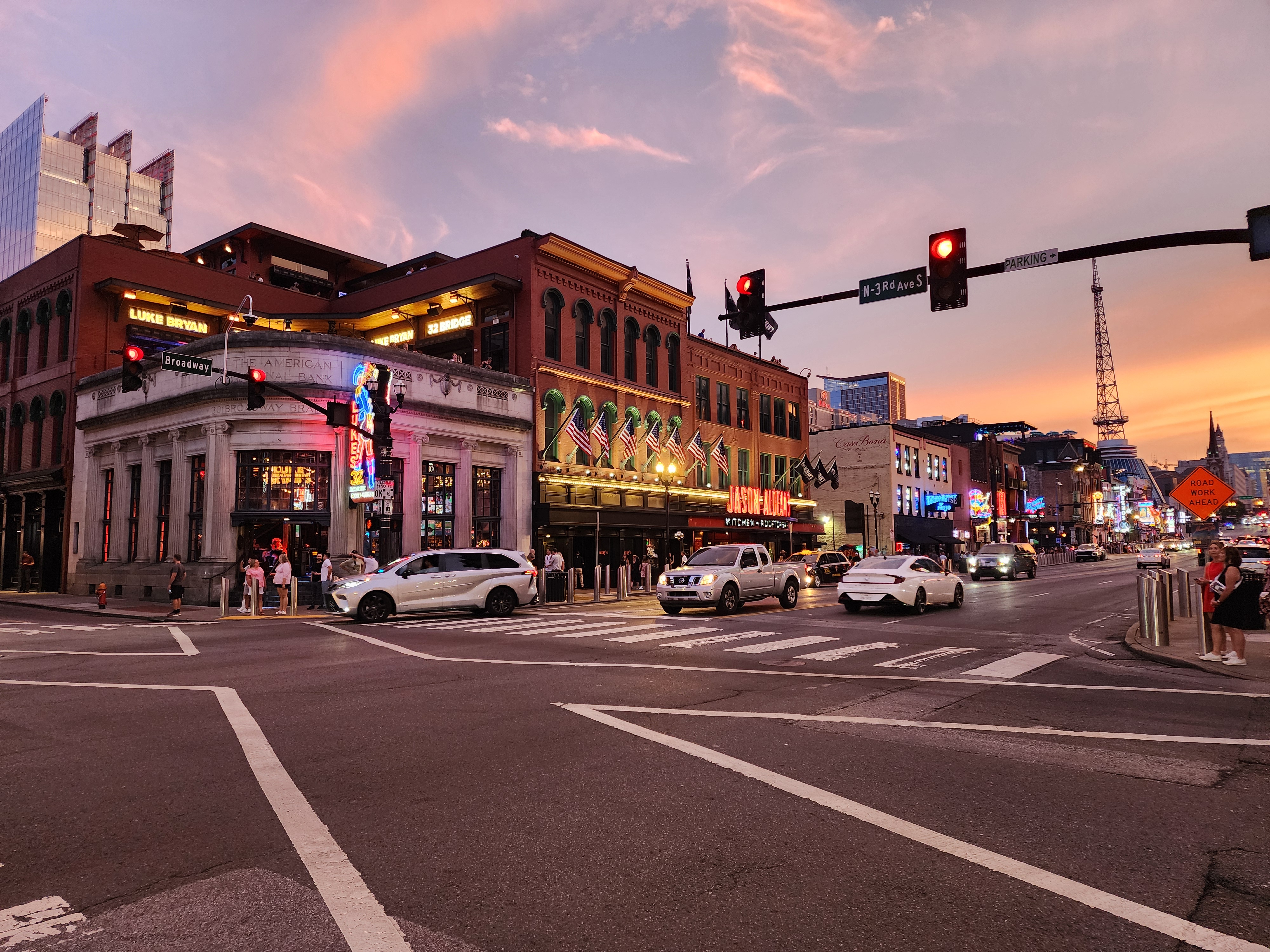 Lower Broadway bars and neon signs at sunset near Third Avenue.