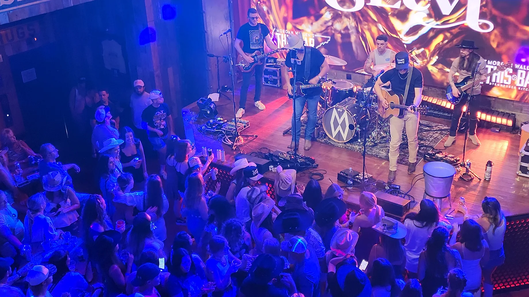 A live band performing inside a Lower Broadway honky tonk with a crowd gathered around the stage.