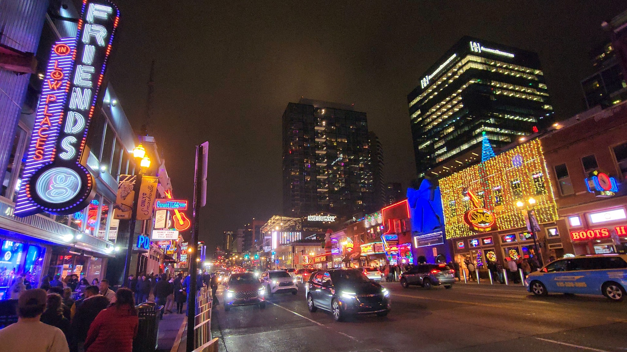 Lower Broadway illuminated by neon signs at night.