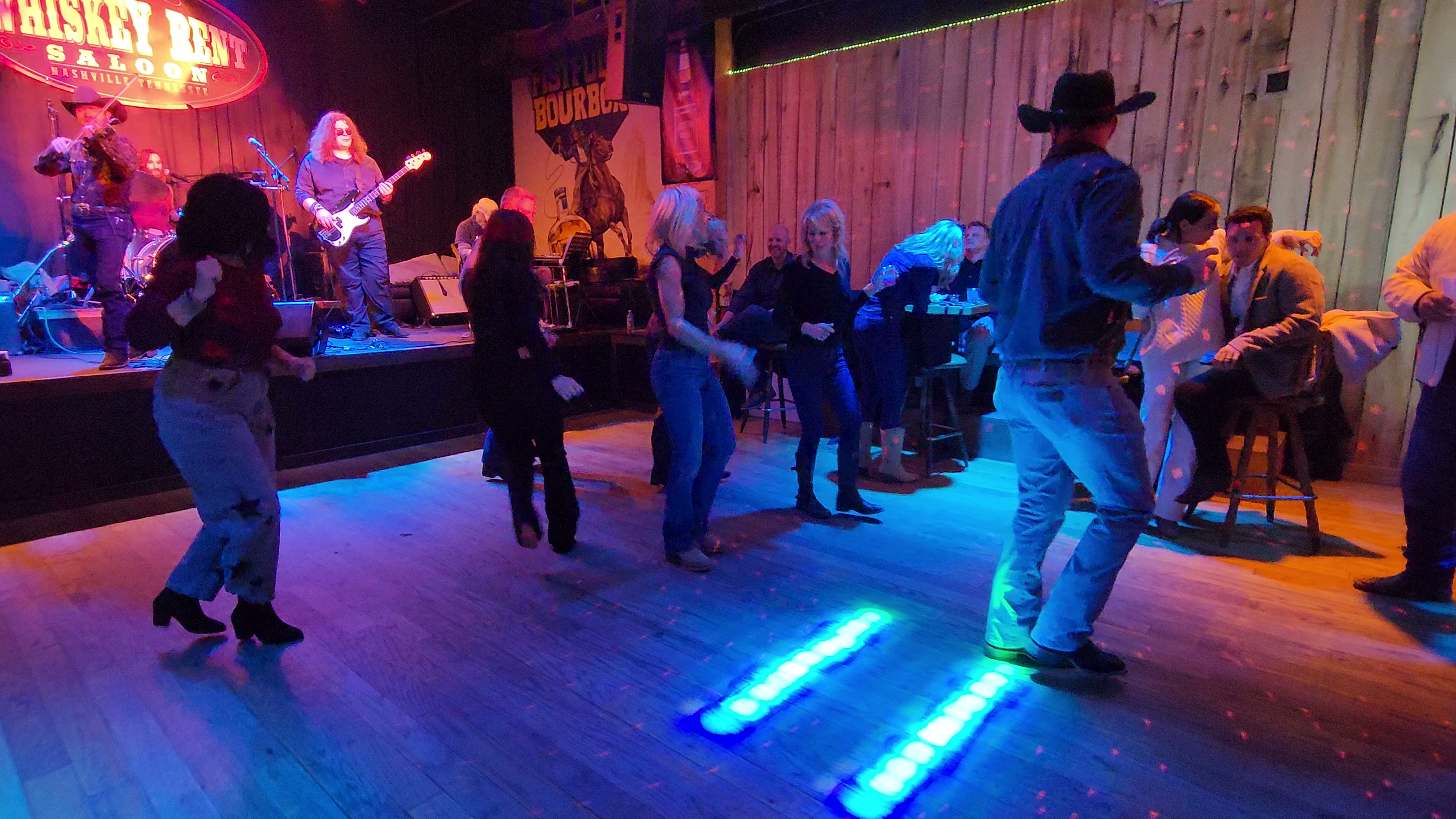 A group follows a line dance on a Nashville dance floor.