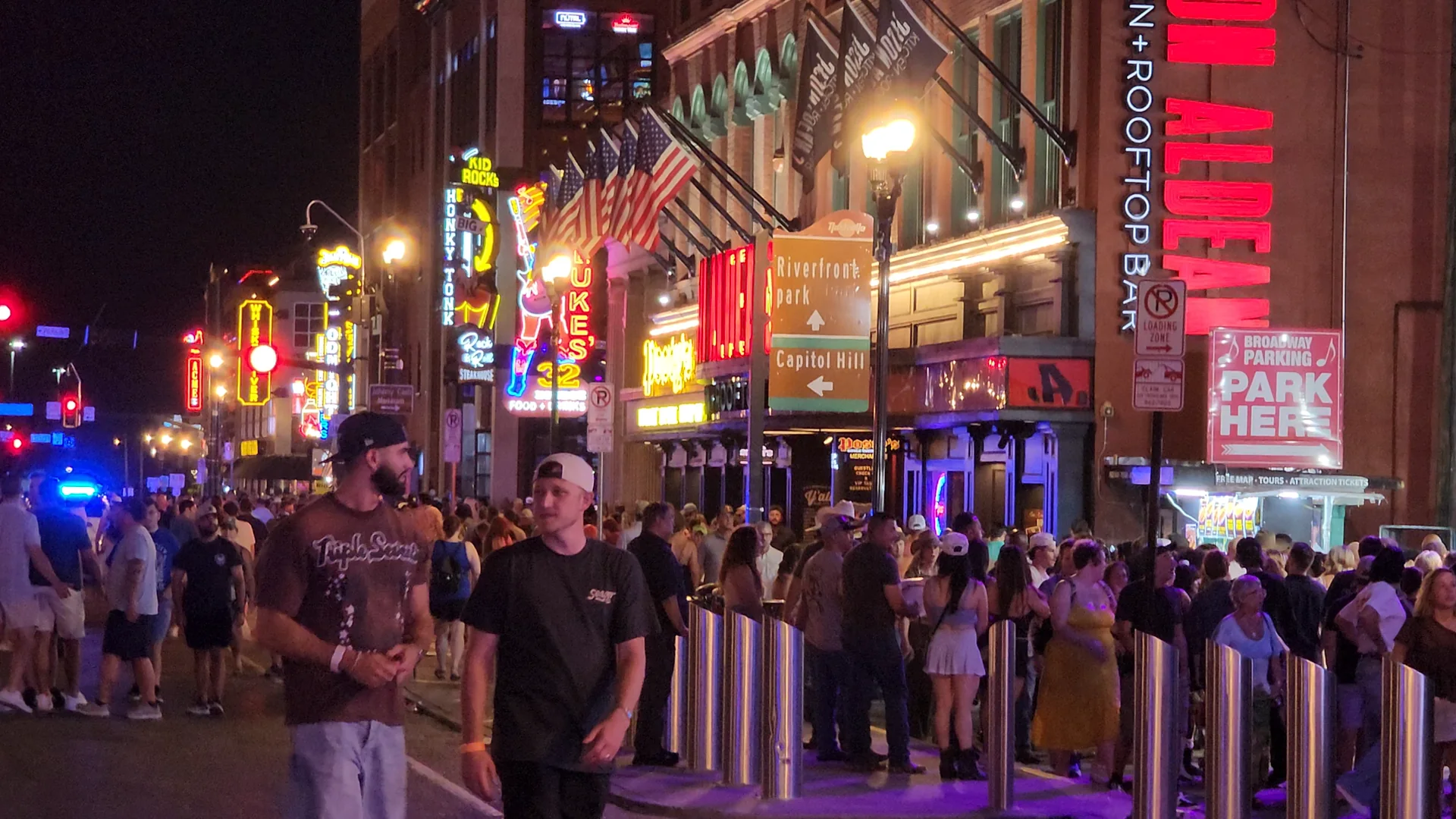 A busy Lower Broadway at night with crowds and neon honky-tonk signs.