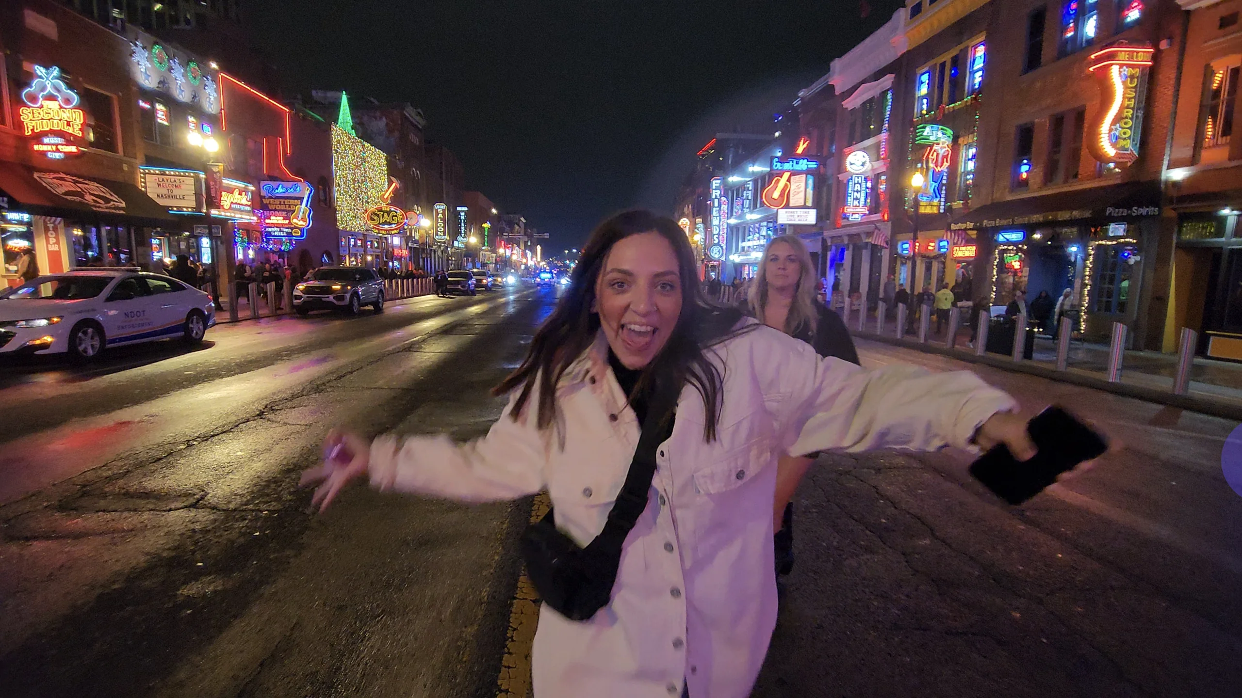 A woman wearing a white jacket on Lower Broadway during the holiday season.